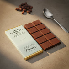 Load image into Gallery viewer, Chocolate bar with packaging and almonds on a wooden surface