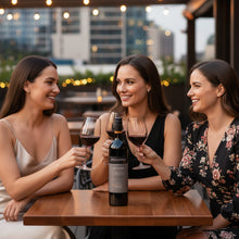 Load image into Gallery viewer, Three women enjoying a bottle of Beresford-Estate-McLaren-Vale-Shiraz wine at a rooftop bar with cityscape in the background