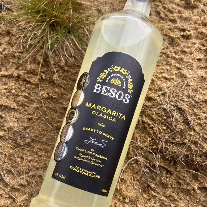 Load image into Gallery viewer, Bottle of Besos Margarita Clasica ready to serve cocktail on a sandy surface