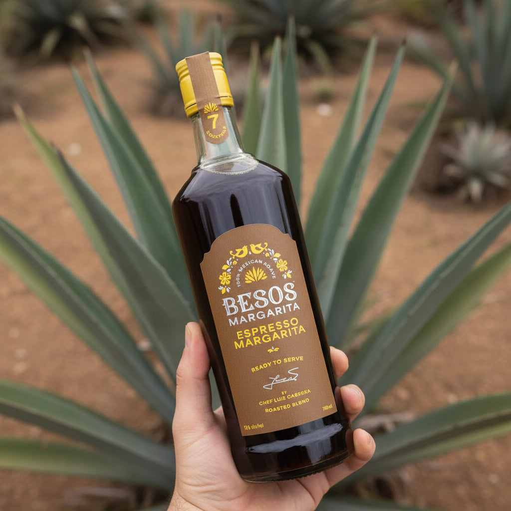 Load image into Gallery viewer, Bottle of Besos Margarita Espresso Margarita held in front of agave plants