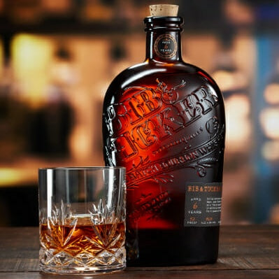 Load image into Gallery viewer, Bottle of Johnnie Walker Blue Label whisky with a glass on a wooden surface.
