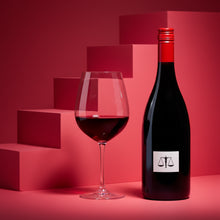 Load image into Gallery viewer, A bottle of Bilancia La Collina Syrah red wine bottle and wine glass on a pink artistic background