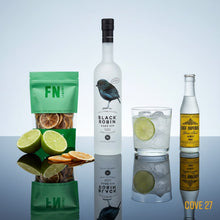 Load image into Gallery viewer, Bottle of Black Robin gin, a cocktail with  lime and ice, a East Imperial Yuzu Tonic Water  bottle and a dried lemons pouch on a reflective surface.