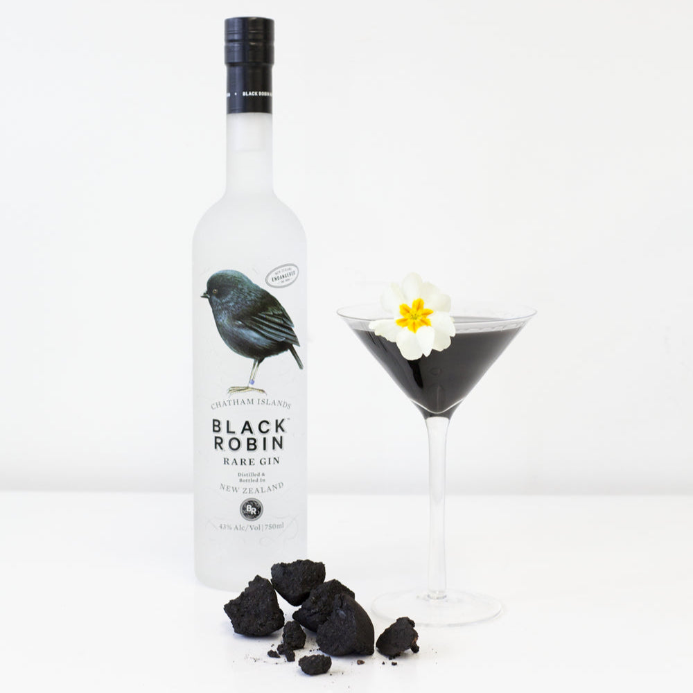 Black Robin Rare Gin bottle with a cocktail and garnishes on a white background