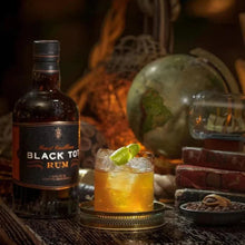 Load image into Gallery viewer, Black Tot Rum bottle with a cocktail garnished with a lime wedge on a rustic table.