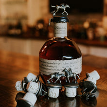 Load image into Gallery viewer, Bottle of Blanton&#39;s bourbon with decorative elements on a wooden surface