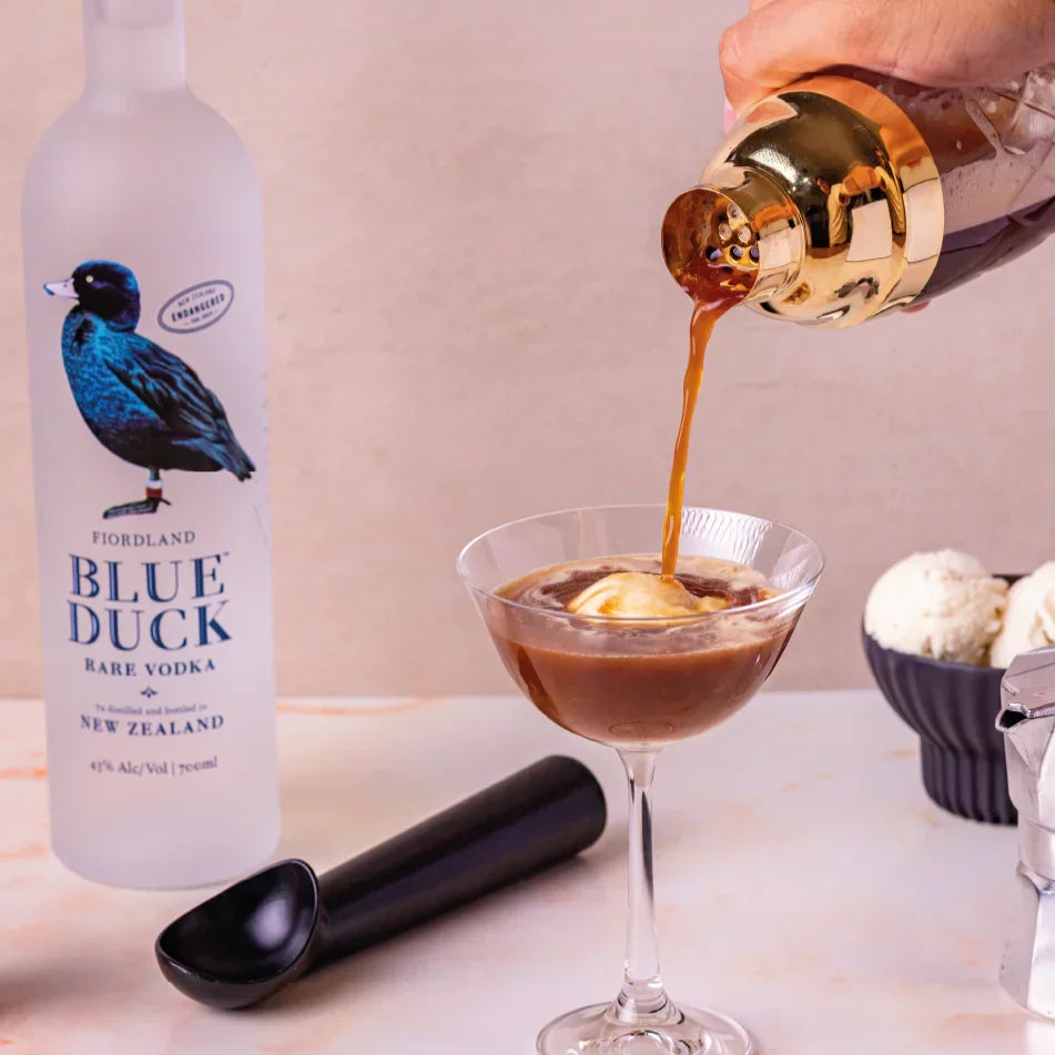 Blue Duck vodka bottle with a cocktail being poured into an espresso martini topped with ice cream