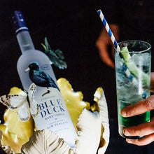 Load image into Gallery viewer, Blue Duck Vodka bottle with a cocktail and lemon garnish on a dark background
