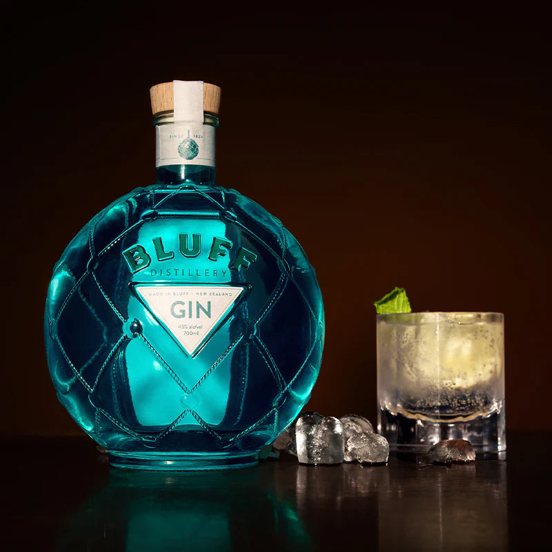 An image of a stunning and unique bottle of Bluff London Dry style gin, 700ml, next to a mouth-watering cocktail