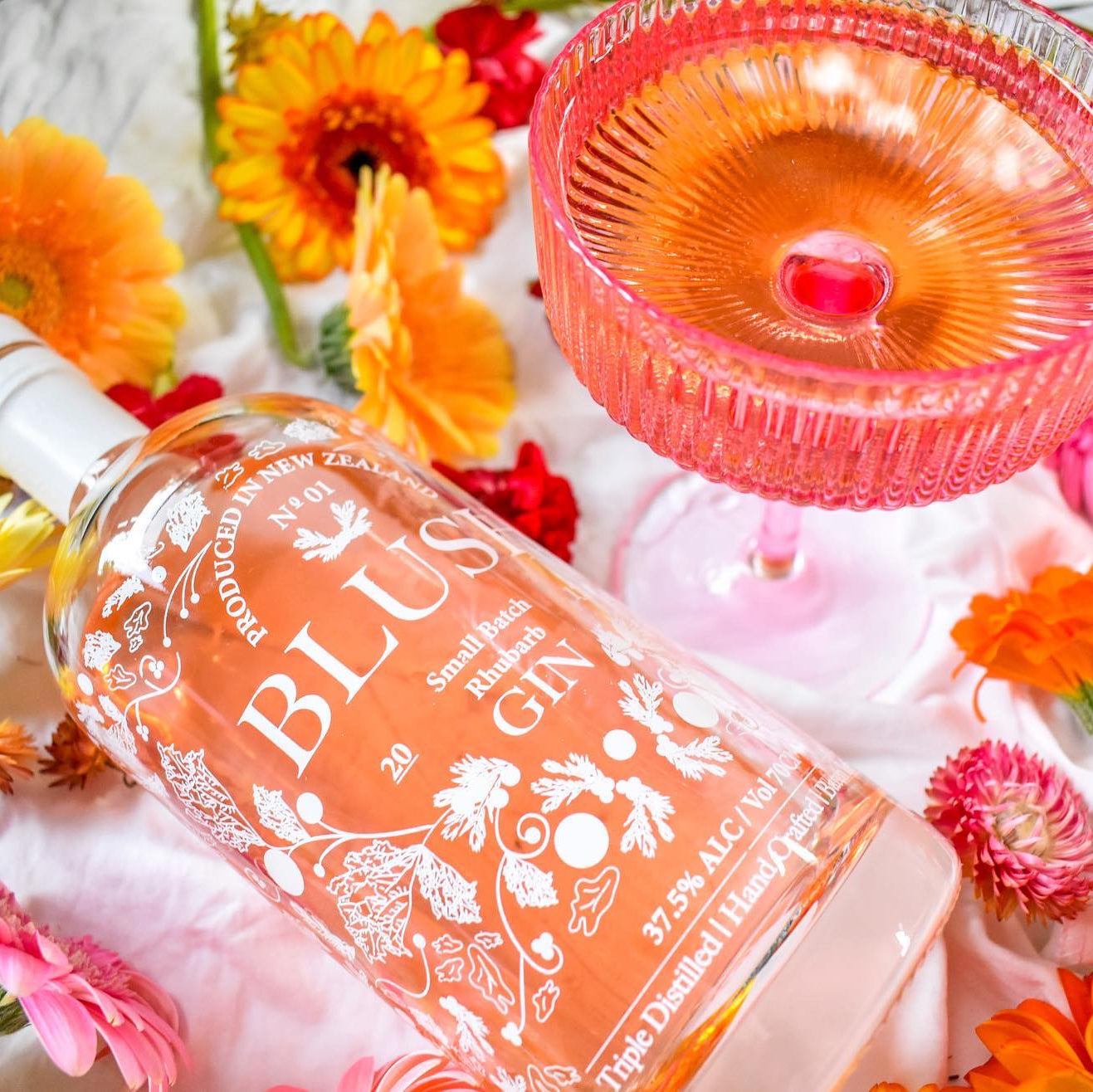 Load image into Gallery viewer, Bottle of Blush Gin surrounded by flowers and a pink glass.