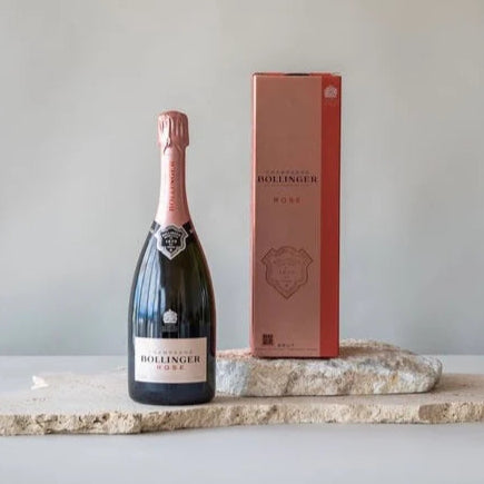 Bollinger rosé champagne bottle and packaging on a marble slab with a plain background