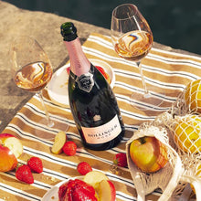 Load image into Gallery viewer, Bollinger rosé champagne bottle with two glasses on a striped cloth by a body of water.