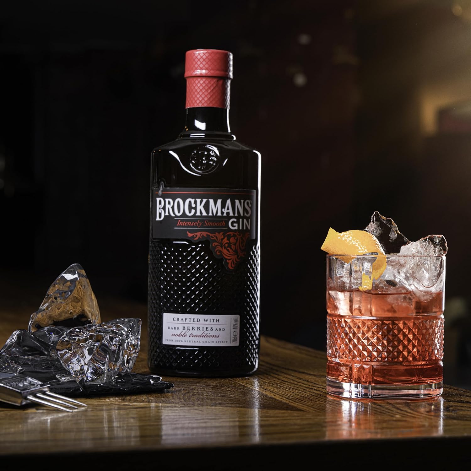 Load image into Gallery viewer, Brockmans Gin bottle with a cocktail on a wooden surface