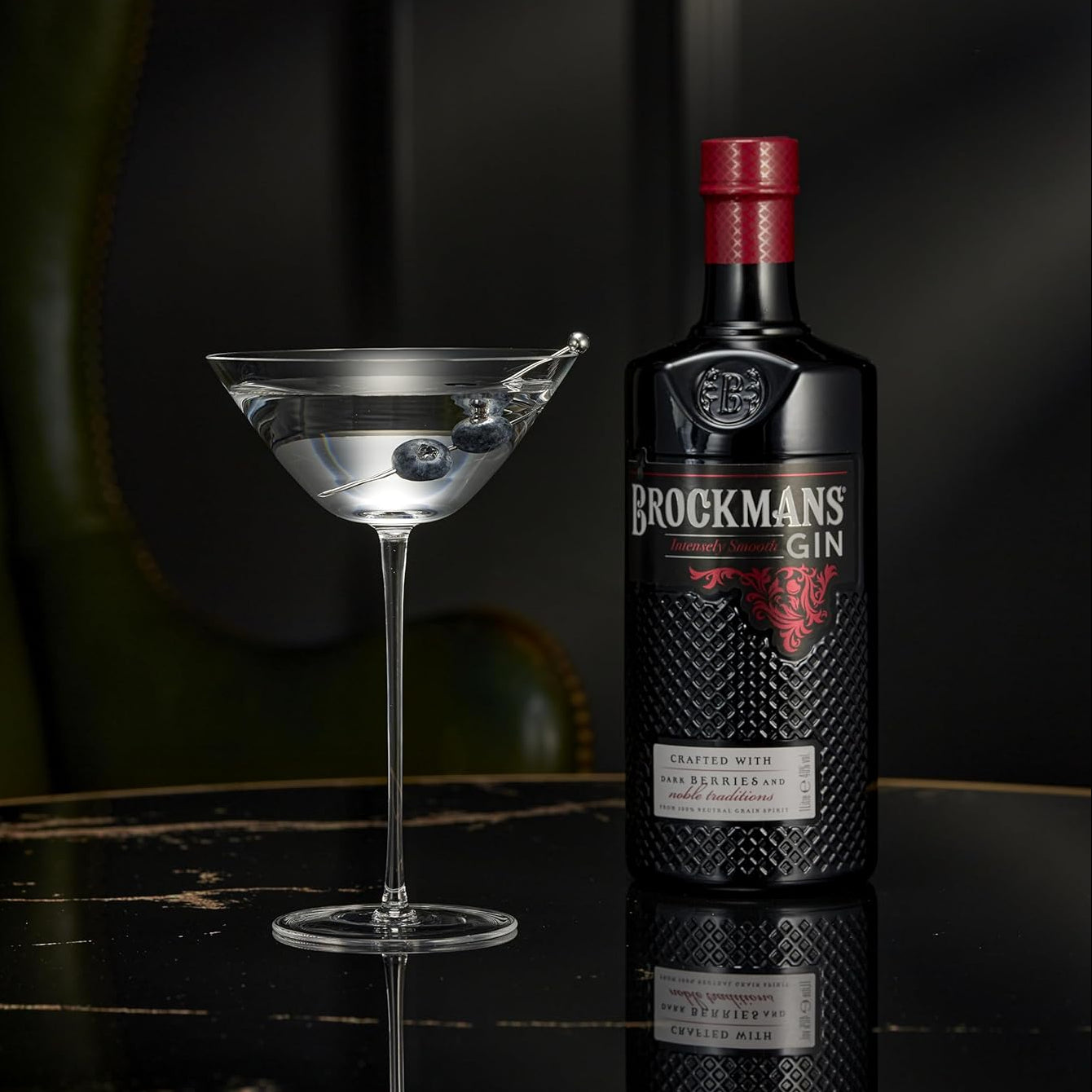 Load image into Gallery viewer, Brockmans Gin bottle with a cocktail glass on a dark surface