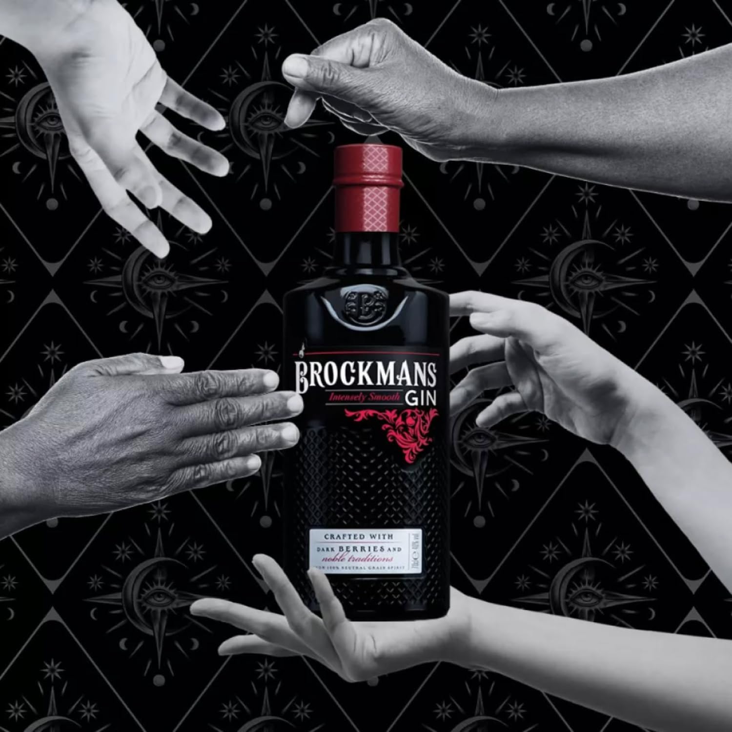 Load image into Gallery viewer, Brockmans Gin bottle held by hands against a black background with white hands reaching towards it.