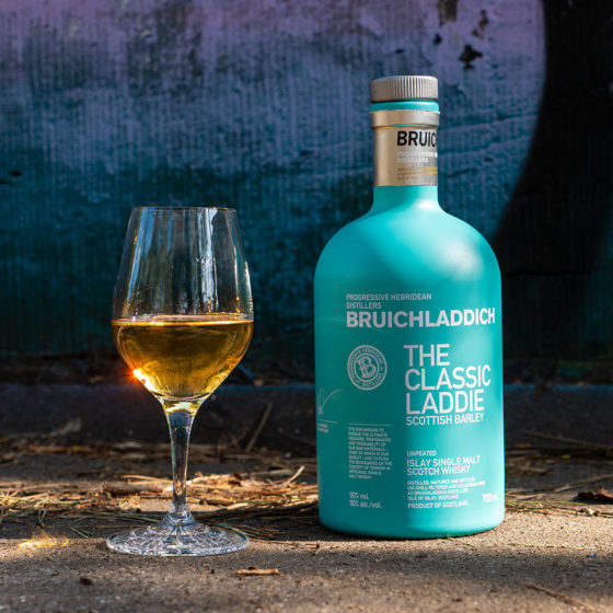 Load image into Gallery viewer, Bruichladdich whisky bottle and glass on a textured surface with a blurred background