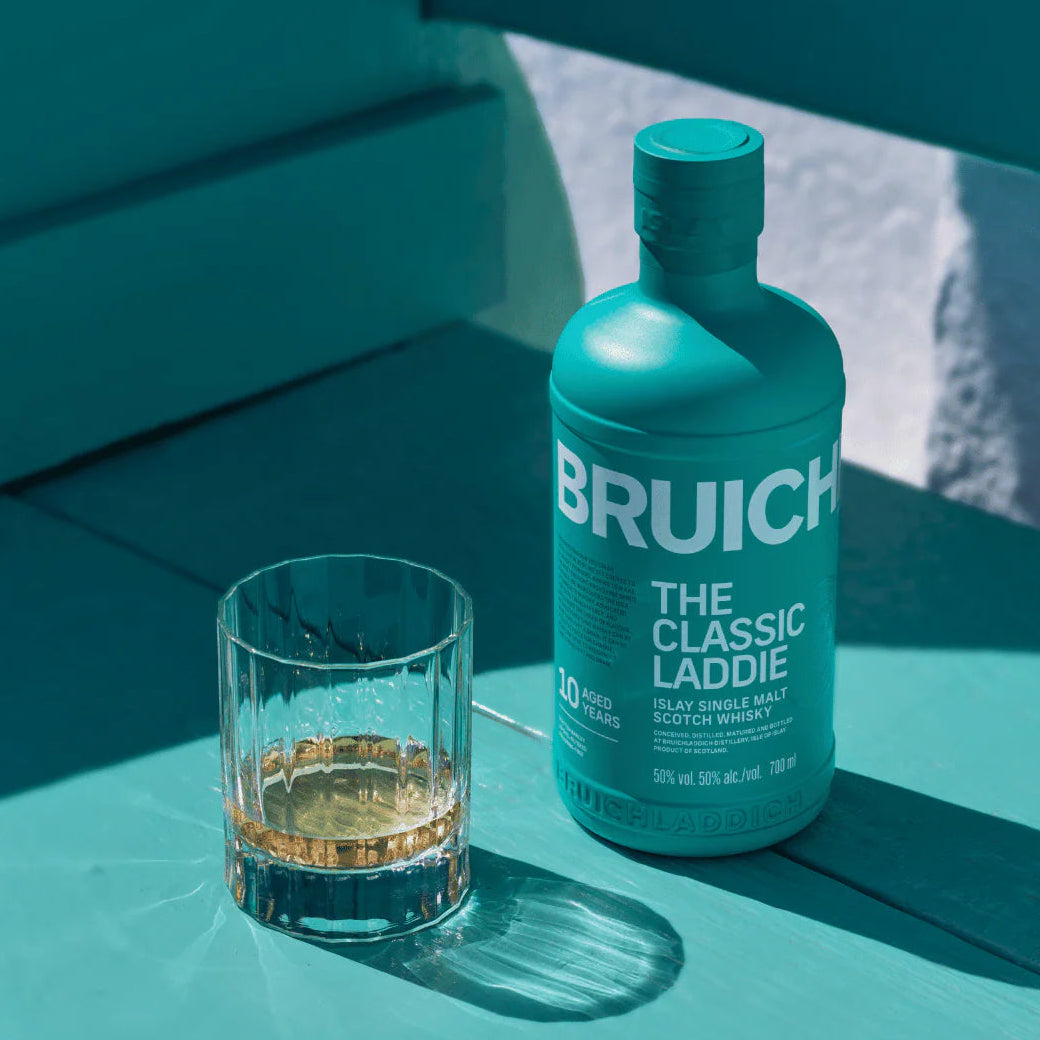 Load image into Gallery viewer, Bruichladdich Classic Laddie whisky bottle and glass on a teal surface