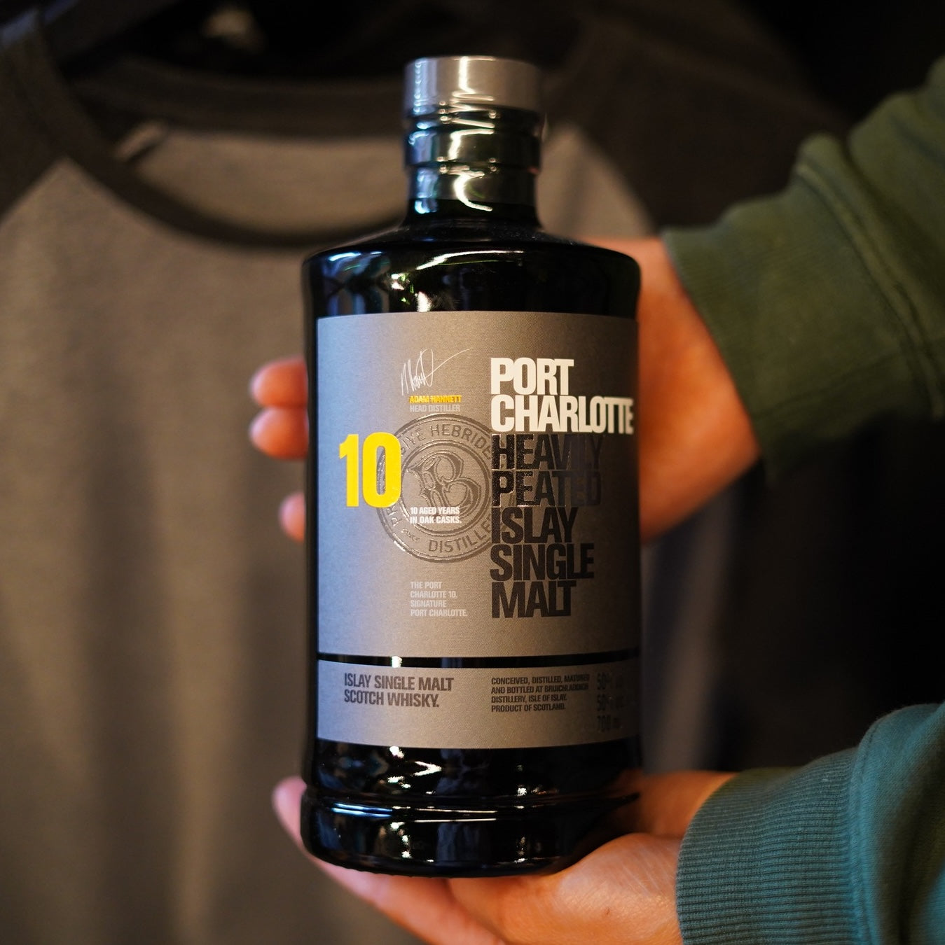 Load image into Gallery viewer, Man holding a bottle of Bruichladdich Port Charlotte 10 year old whisky in his hand
