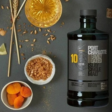 Load image into Gallery viewer, A bottle of  Bruichladdich Port Charlotte 10 year old whisky on a table with a tumbler full and some fruit