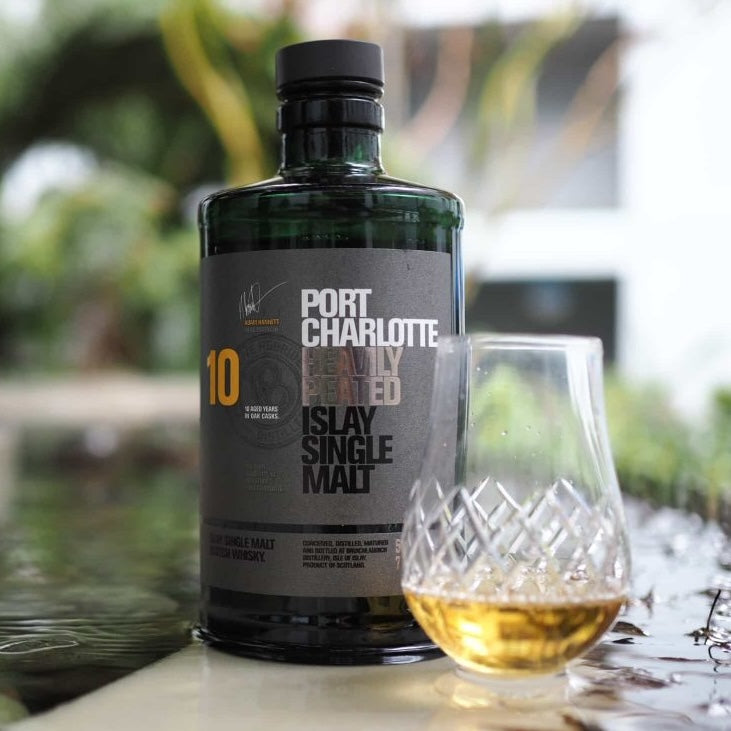 Load image into Gallery viewer, A bottle of Bruichladdich Port Charlotte 10 year old whisky and and a half full glass of whisky