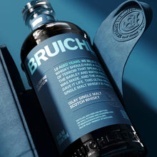 Load image into Gallery viewer, Bruichladdich 18 year old whisky bottle with leather strap on a blue background