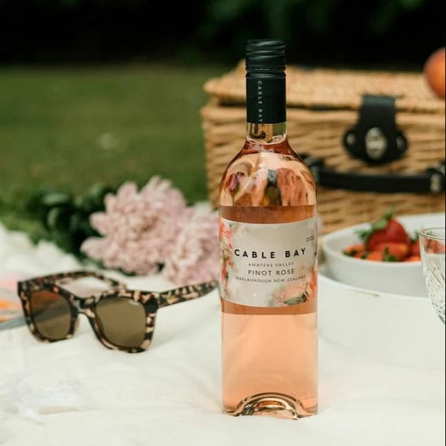 Load image into Gallery viewer, a bottle of rose wine on a pic nic blanket with some strawberries. 