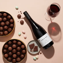Load image into Gallery viewer, Bottle of Cable Bay Reserve Syrah wine with chocolates and a glass of red wine on a pink background