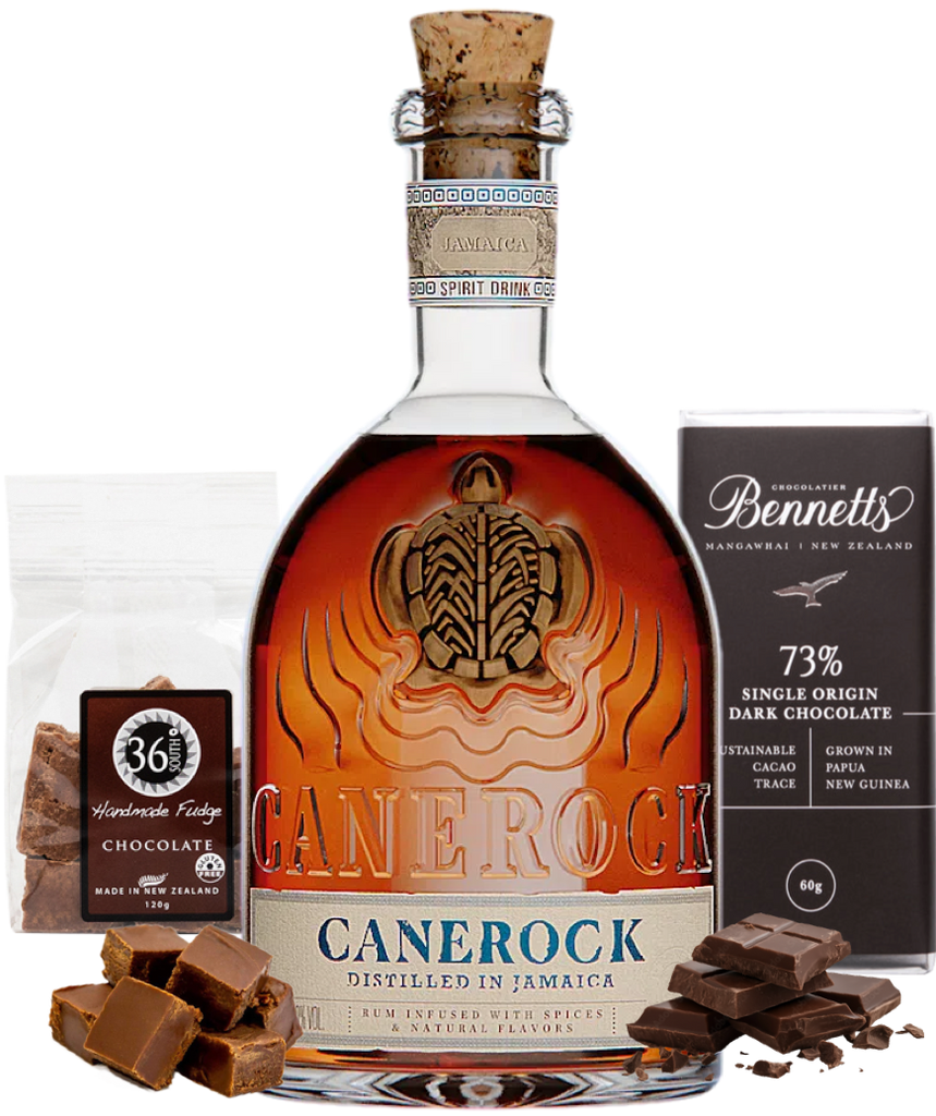 A bottle of Canerock Jamaican Spiced Rum, displayed with a bag of 36 Degrees Handmade Chocolate Fudge, a dark Bennett's chocolate bar, and chocolate pieces on a white background.