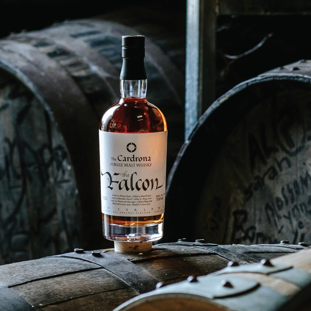 Bottle of Falcon whiskey on wooden barrels in a warehouse setting