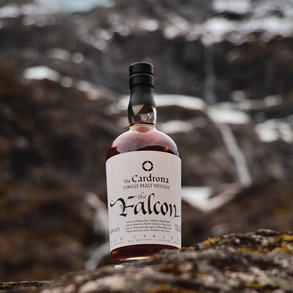 Bottle of The Cardrona The Falcon whisky on a rocky surface with a blurred natural background