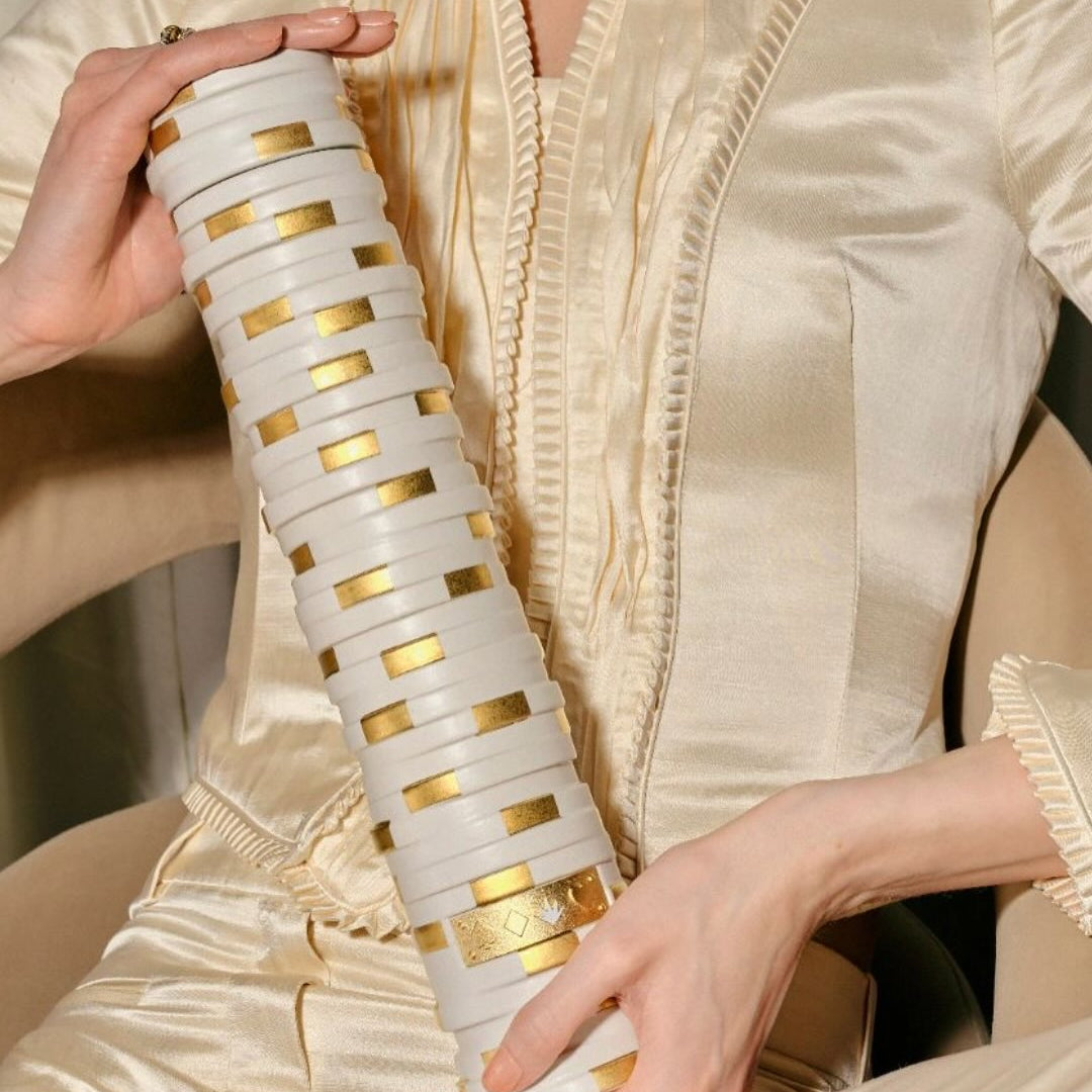 Load image into Gallery viewer, Woman holding a bottle of CasAzar Joven Tequila with gold accents, wearing a coloured outfit.
