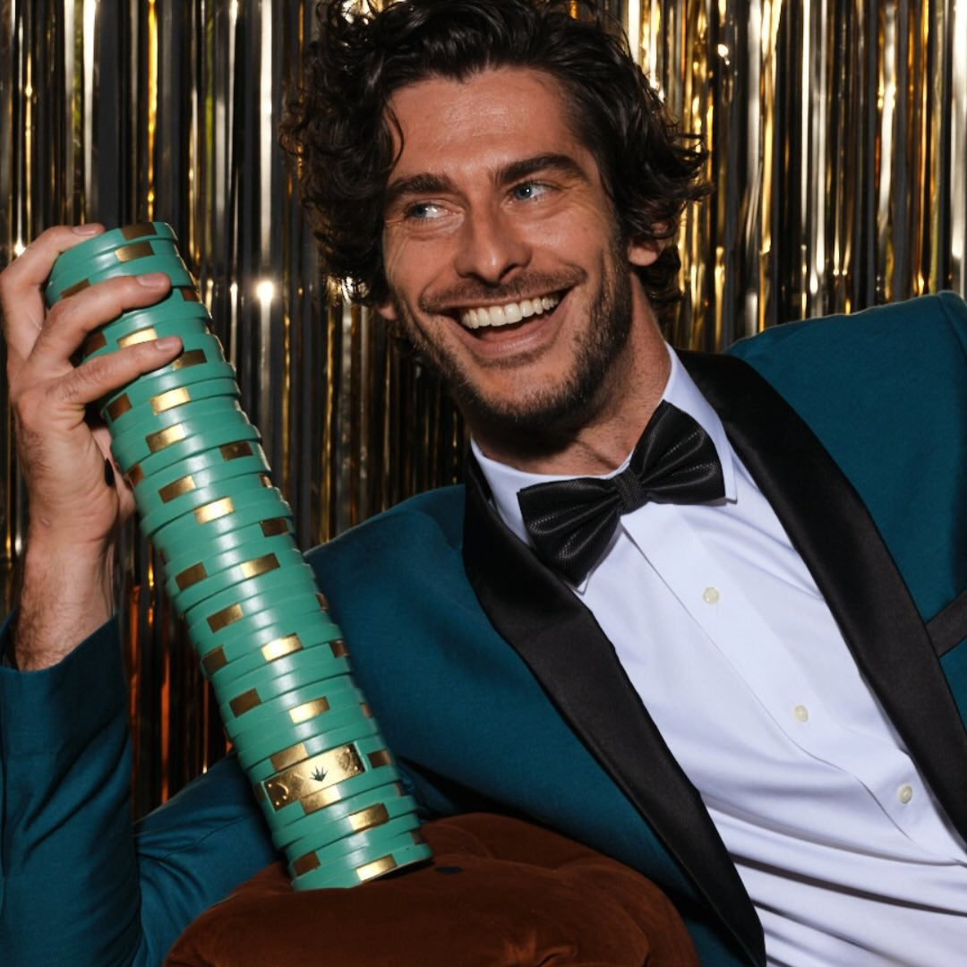 Load image into Gallery viewer, Man in a tuxedo holding a bottle of CasAzar Reposado Tequila against a metallic curtain background