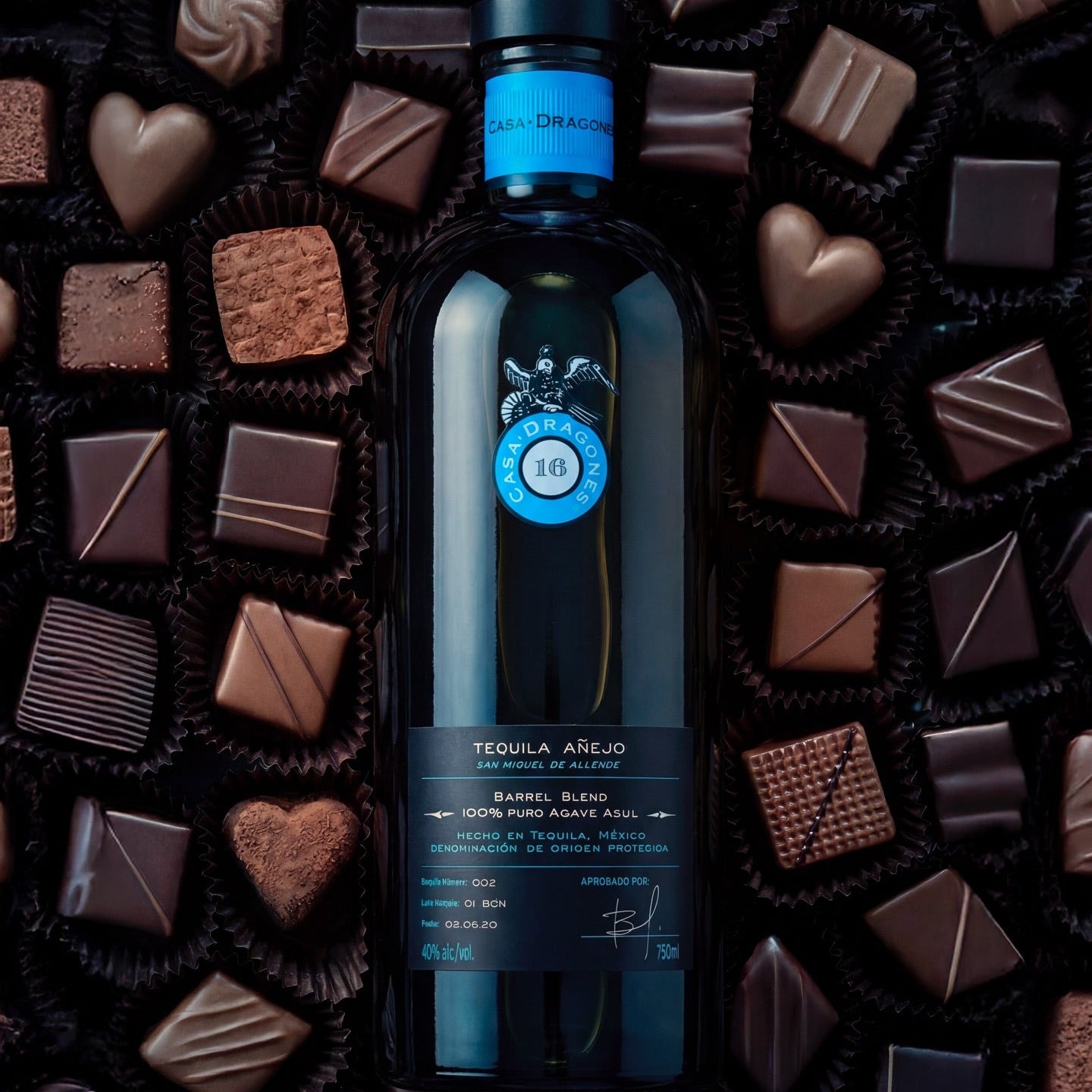 Load image into Gallery viewer, Casa Dragones Anejo Tequila bottle surrounded by chocolates on a dark background