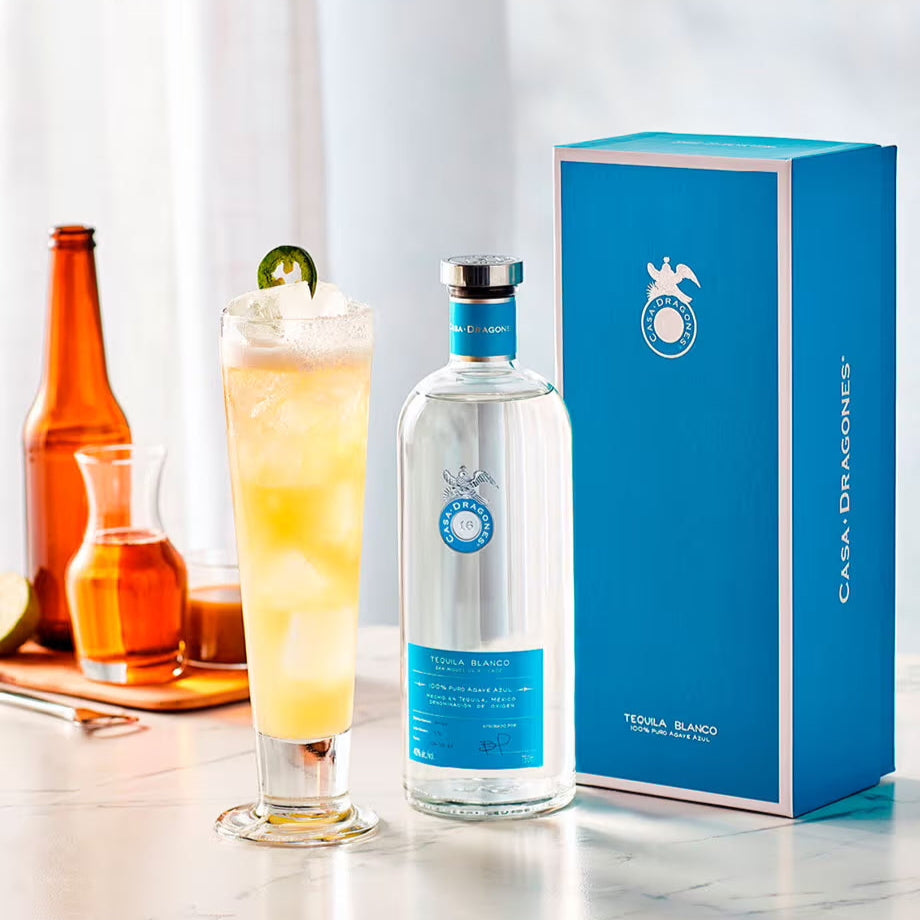 Casa Dragones Blanco Tequila bottle and packaging with a cocktail on a marble surface