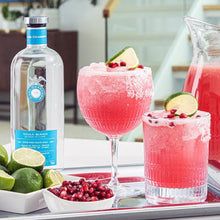 Load image into Gallery viewer, Two pink cocktails with garnishes on a tray with a bottle of Casa Dragones Blanco Tequila and limes.