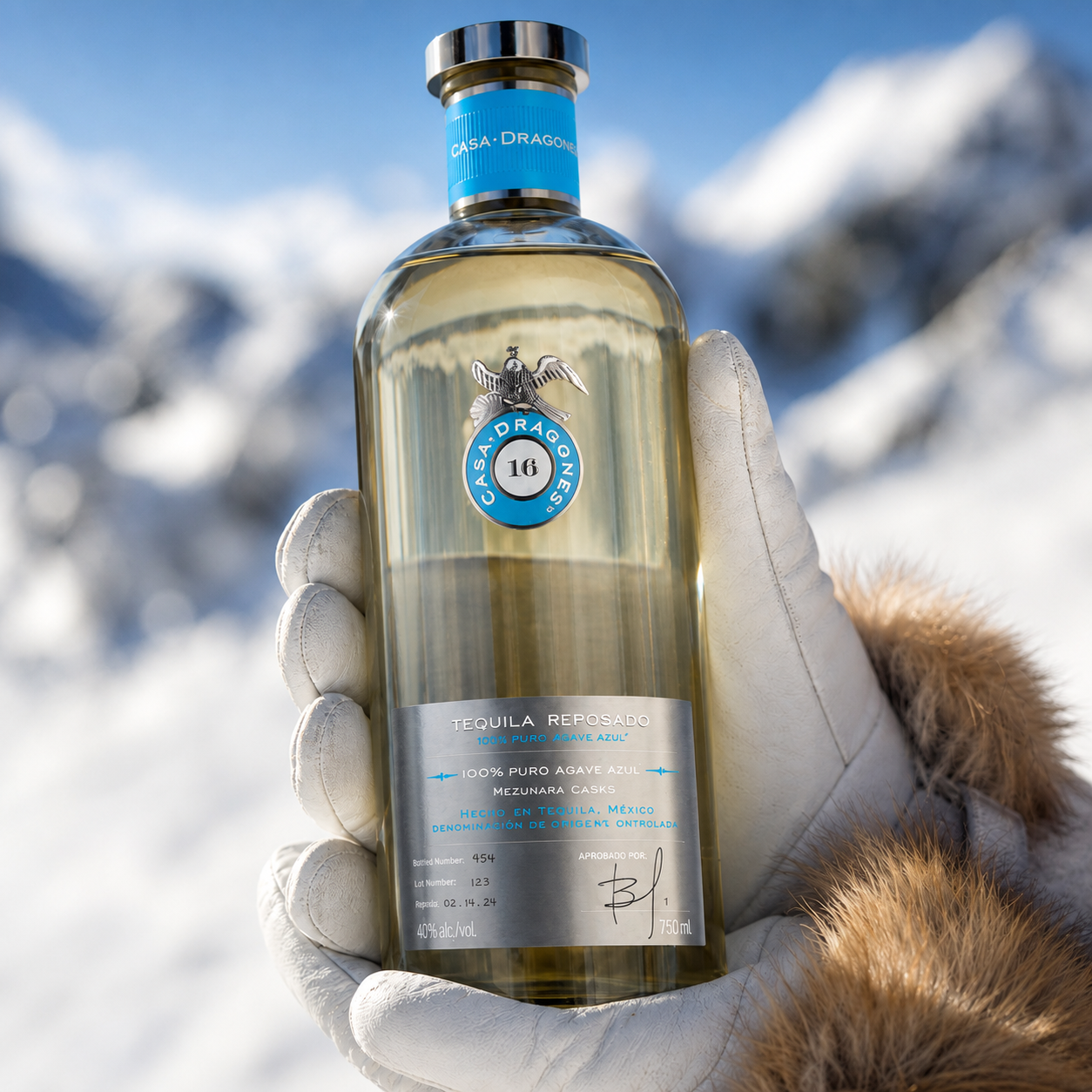 Load image into Gallery viewer, Hands in gloves holding a bottle of Casa Dragones Reposado Mizunara Tequila in the ski fields with blurred snowy mountains in the background.