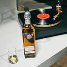 Load image into Gallery viewer, Bottle of Casa Noble Reposado and a glass on a table next to a record player.