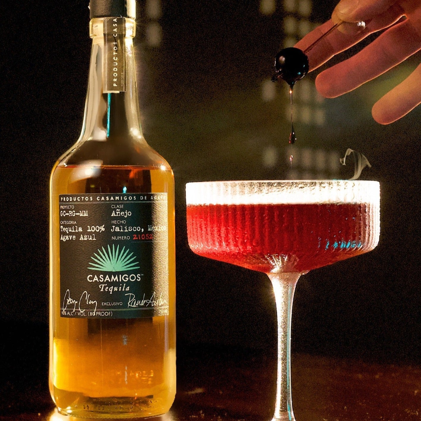 Load image into Gallery viewer, Bottle of Casamigos tequila with a cocktail being poured in the background.