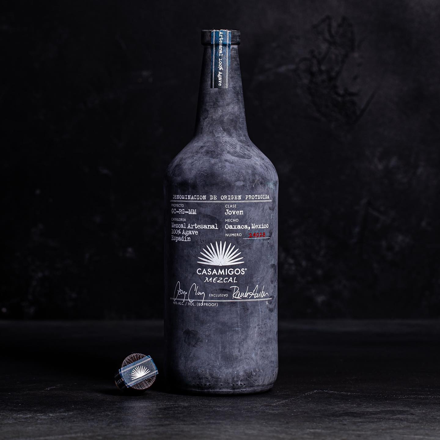 Load image into Gallery viewer, Dark black bottle with 'Casamigos Mezcal' label on a black background