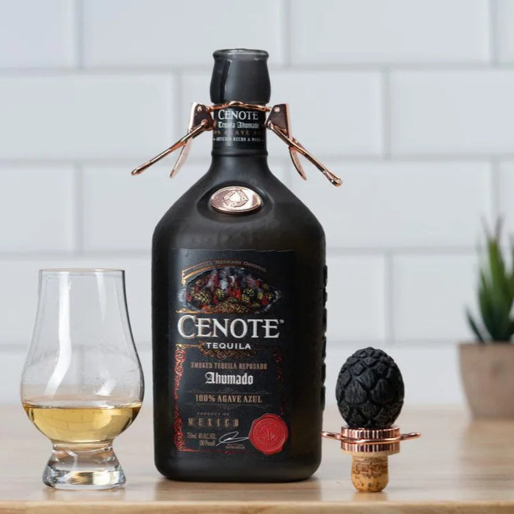Cenote tequila bottle with a glass of tequila on a wooden surface.