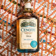 Load image into Gallery viewer, Cenote Tequila bottle on a textured orange and white background