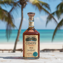 Load image into Gallery viewer, Cenote Tequila bottle on a wooden surface with a beach and palm trees in the background