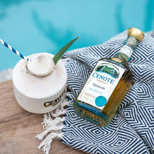 Load image into Gallery viewer, Cenote Reposado tequila bottle with a coconut drink and straw on a poolside table.