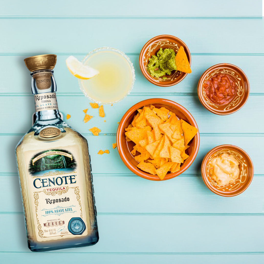 Load image into Gallery viewer, Cenote Reposado tequila bottle with nacho ingredients on a light blue wooden surface