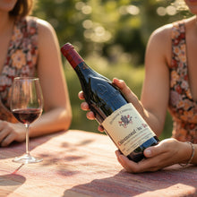 Load image into Gallery viewer, Person holding a bottle of Charvin Châteauneuf-du-Pape red wine with a glass outdoors.