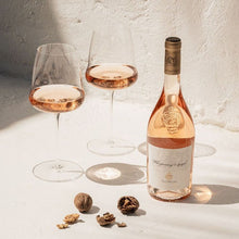 Load image into Gallery viewer, Bottle and two glasses of rose wine on a light surface with a textured wall background