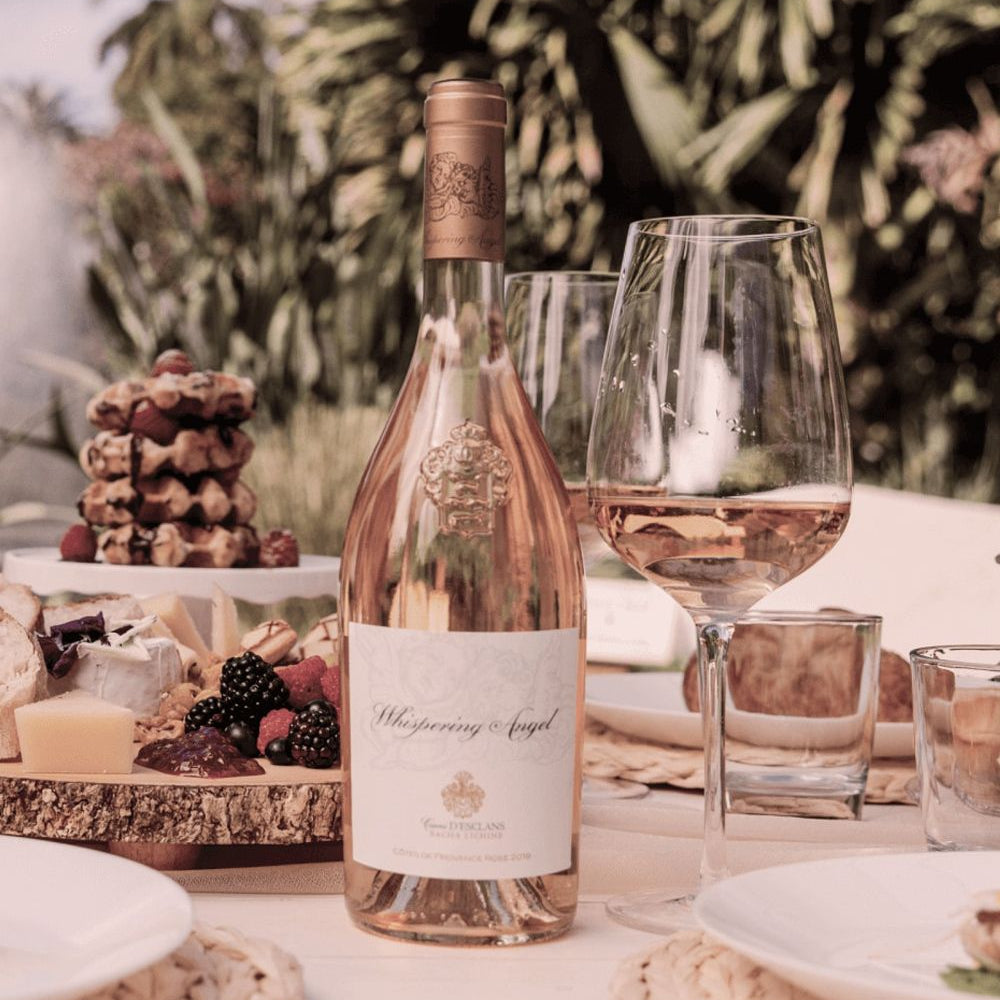 Load image into Gallery viewer, Bottle of Rosé wine with a glass on a table outdoors with snacks and candles.