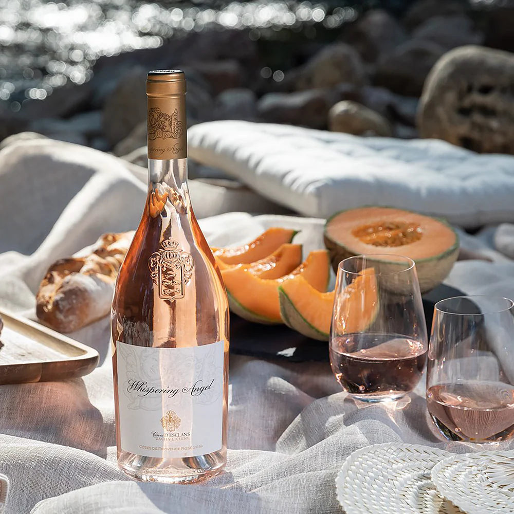 Load image into Gallery viewer, Bottle of Whispering Angel rosé wine on a beach setting with melon and glasses.