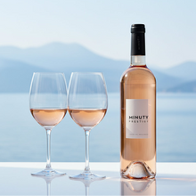 Load image into Gallery viewer, Bottle of Minuty Prestige rosé wine with two glasses filled with the wine against a scenic background.
