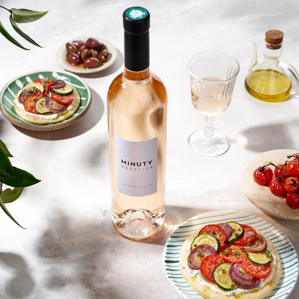 Bottle of Minuty Rosé wine with plates of food on a light surface